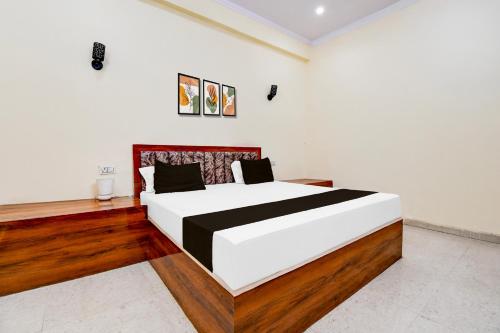a bedroom with a large white bed with wooden floors at Hotel O SRS Inn Guest House in Gorakhpur