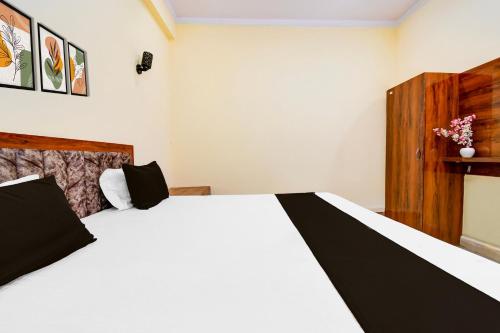 a bedroom with a white bed with black and white sheets at Hotel O SRS Inn Guest House in Gorakhpur