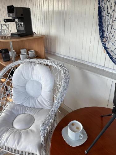a wicker chair with a table and a cup of coffee at Przystań Pod Wieżą in Władysławowo