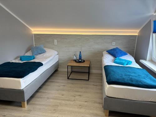 two beds in a room with a side table at Przystań Pod Wieżą in Władysławowo