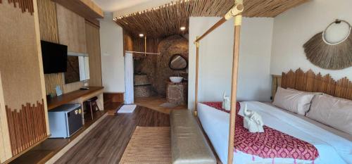 a bedroom with a bed and a tv in a room at The Rock Samui Beachfront Villas - Sha Plus Hotel in Lamai