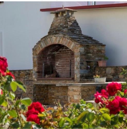 an outdoor brick oven with red flowers in the foreground at Harmony Seaside Pelion in Platanias