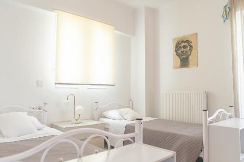 a white room with two beds and a window at Island Memories Apartment in Ampavris