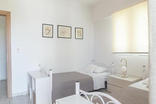 a white bedroom with two beds and a table at Island Memories Apartment in Ampavris