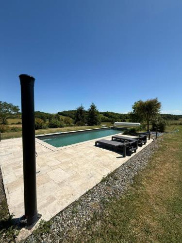 une piscine avec une rangée de chaises longues à côté d'un poteau dans l'établissement Le clos du Broca, à Clermont-Pouyguilles