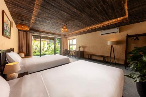 a bedroom with two beds and a large window at Scenic Mountain Ecolodge Ninh Binh in Ninh Binh