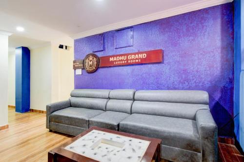 sala de estar con sofá y pared púrpura en Hotel O Madhu Grand Luxury Rooms, en Hyderabad