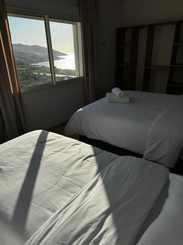 two beds in a hotel room with a window at Séjour Bab Diki in Melîyech