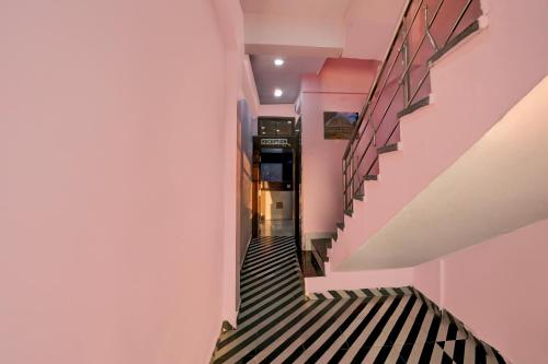 Una escalera en un edificio con paredes rosas y rayas blancas y negras. en Hotel O The Shark Palace, en Bhopal