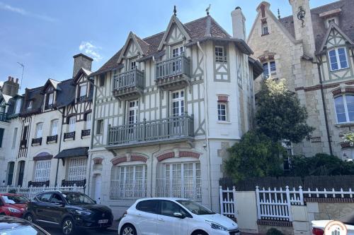 une grande maison avec des voitures garées devant elle dans l'établissement La Villa Mirabeau, à Deauville