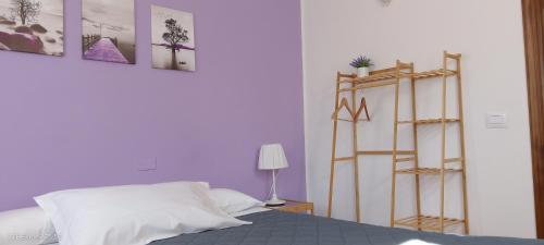 a bedroom with purple walls and a bed and a shelf at La Castagna Matta in Albareto