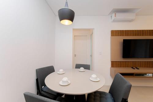 a dining room with a white table and chairs at Condomínio Temple Batel | Gonzaga Stays in Curitiba