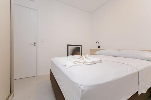 a white bedroom with a large white bed at Condomínio Temple Batel | Gonzaga Stays in Curitiba