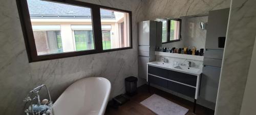 ein Badezimmer mit Badewanne und Waschbecken und einem Fenster in der Unterkunft Villa Neves in Saint-Cyr-sur-Loire