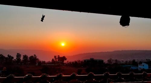 a view of the sunset from a window with a butterfly at Silver Petal Hospitality in Panchgani