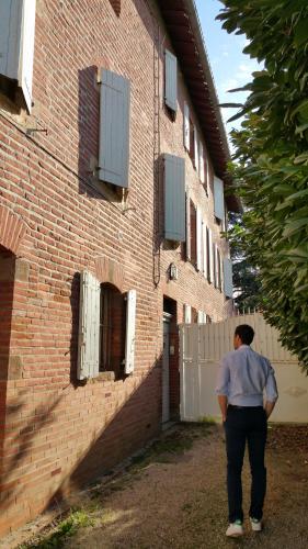 a man standing in front of a brick building at B&B La Maison de Julia in Albi