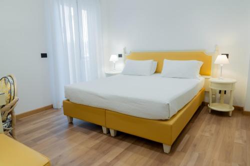 a bedroom with a yellow bed with white sheets and white pillows at Hotel Florida Lerici in Lerici