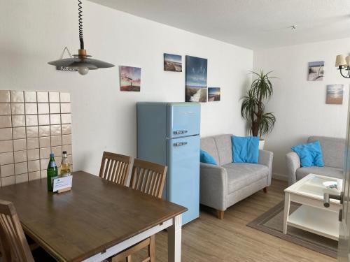 Una cocina y una sala de estar con una mesa y un refrigerador azul. en Haus Carstensen-Bungalow 1, en Wyk auf Föhr