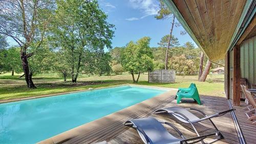 - une piscine avec des chaises sur une terrasse en bois dans l'établissement M-Clairière aux Chevreuils 01-Moliets Maison avec piscine privée proche océan, à Moliets-et-Maa
