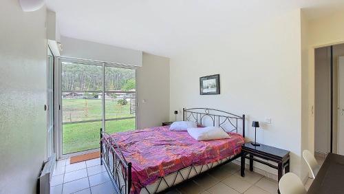 une chambre avec un lit et une grande fenêtre dans l'établissement M-Clairière aux Chevreuils 01-Moliets Maison avec piscine privée proche océan, à Moliets-et-Maa