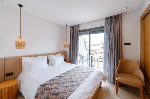 a bedroom with a bed and a chair and a window at Spinoza House Appart Hôtel in Casablanca