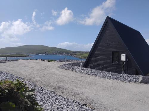 a black building on the side of a body of water at Wild Atlantic Pods in Portmagee