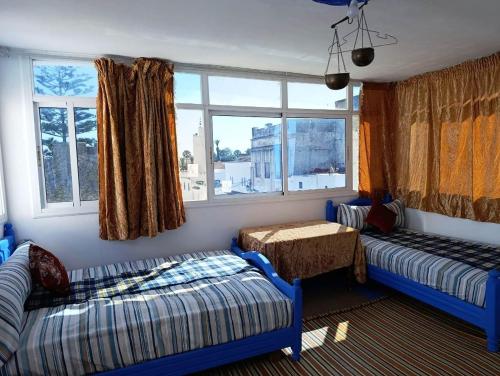 a room with two beds and a couch and windows at Al Medina Asilah AhibbaK in Asilah