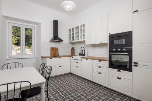 a kitchen with white cabinets and a table with chairs at Apartment Nina in Bakar