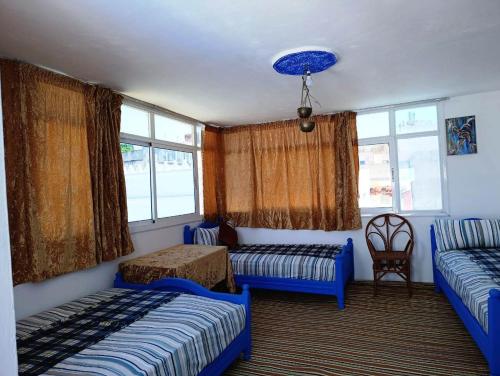 a bedroom with two beds and a couch and windows at Al Medina Asilah AhibbaK in Asilah