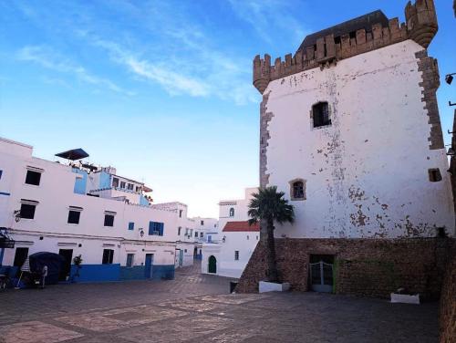 a tall white building with a palm tree next to it at Al Medina Asilah AhibbaK in Asilah
