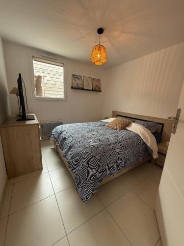 a bedroom with a bed and a television in it at L'étoile des pins in Longeville-sur-Mer