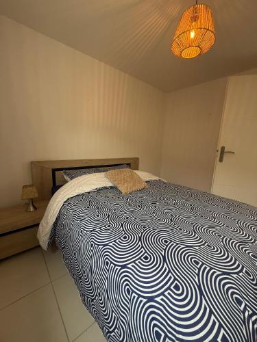 a bedroom with a bed with a black and white comforter at L'étoile des pins in Longeville-sur-Mer