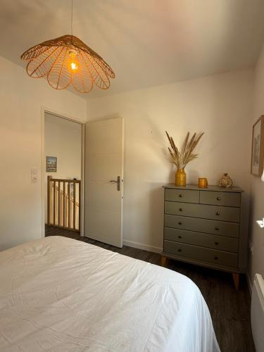 a bedroom with a bed and a dresser and a chandelier at L'étoile des pins in Longeville-sur-Mer