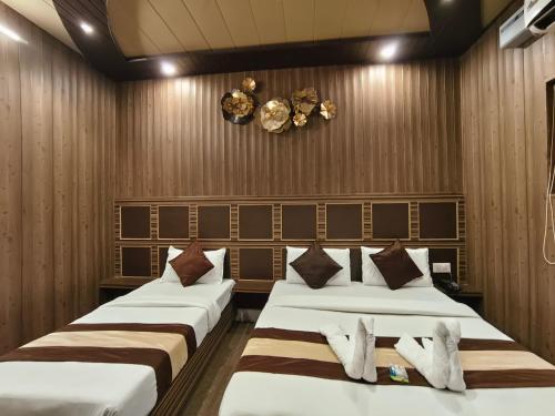 two beds in a room with wooden walls at Hotel Pardesi,Har ki pauri Road Haridwar in Haridwār