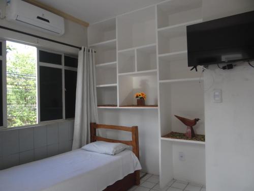 um quarto com uma cama, uma TV e uma janela em São luís Hostel em São Luís