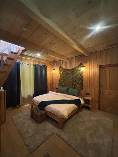 a bedroom with a bed in a room with wooden walls at Kath Kuni Cafe & Stay Shangarh in Shangarh