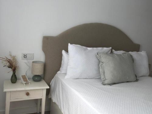 a bed with white pillows and a table with a night stand at Fantástico apartamento "Sol y Sal" en Cala'n Bosch in Cala'n Bosch
