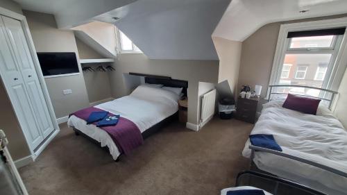 a bedroom with two beds and two windows at Leecliff Guest House in Blackpool