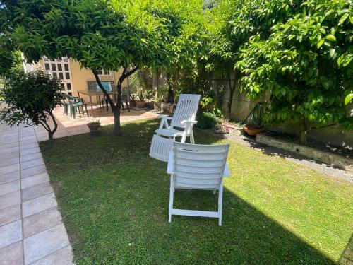 two white chairs sitting on the grass in a yard at Il Marasio, relax vicino al mare in Carrara