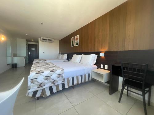 a bedroom with a bed and a desk with a chair at Flats no Ritz Suítes in Maceió