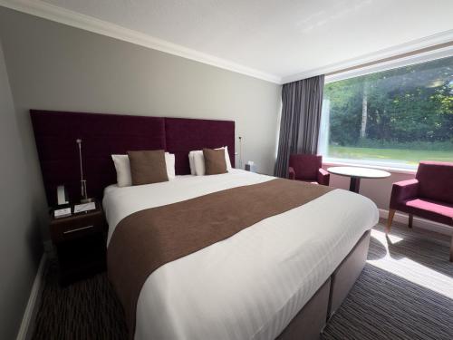 a hotel room with a large bed and a window at The Mount Country Manor Hotel & Golf Wolverhampton in Wolverhampton