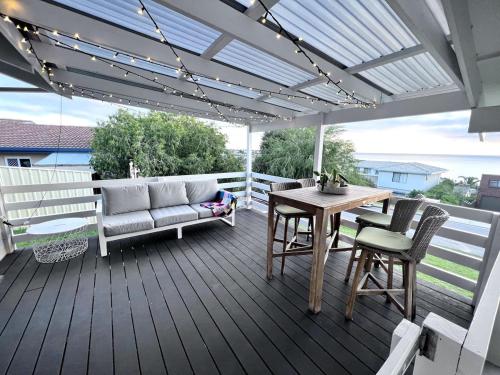 a wooden deck with a table and chairs and a couch at Hallett Cove Sunset Getaway in Hallett Cove