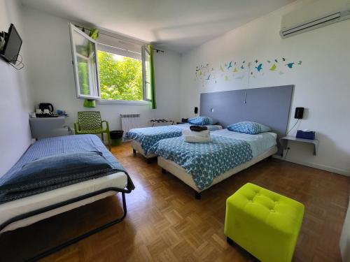 - une chambre avec deux lits et une chaise verte dans l'établissement Maison VENITIA, à Aussonne