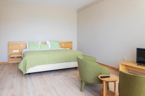 a bedroom with a bed and two chairs and a television at Quinta da Torre - Anselmo Mendes in Cortinhas