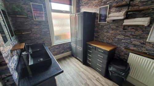 a bathroom with a sink and a stone wall at Leecliff Guest House in Blackpool