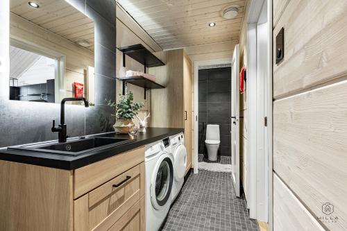 a kitchen with a sink and a washing machine at Villa Cloudberry by Hilla Villas in Kittilä