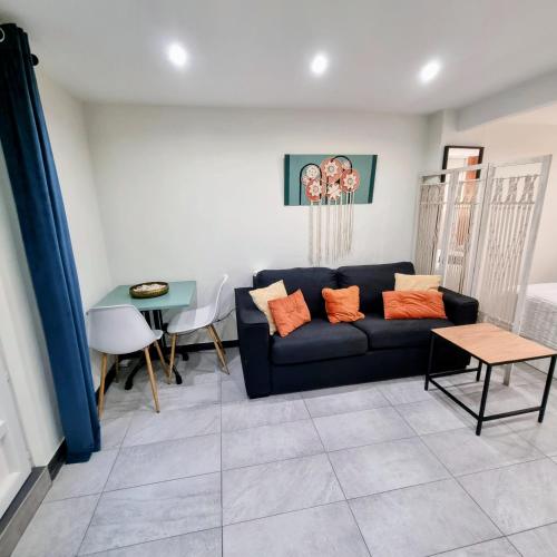 un salon avec un canapé noir et une table dans l'établissement Spacious studio full of charm, recently updated, à Nice
