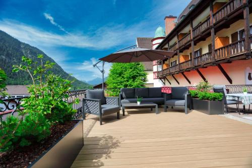 a patio with chairs and an umbrella on a balcony at Hotel Klosterhotel Ludwig der Bayer in Ettal