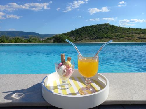 a tray with two drinks on a table next to a pool at Z House kuća za odmor in Blagaj