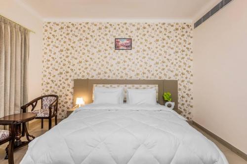 a bedroom with a large white bed and a table at Eco-chic haven in Gurgaon with balcony in Gurgaon